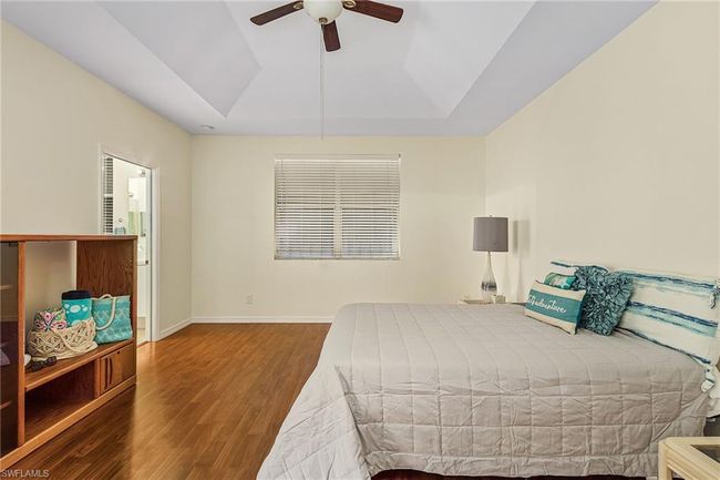 Bedroom featuring a tray ceiling, baseboards, wood finished floors, and a ceiling fan | Image 14