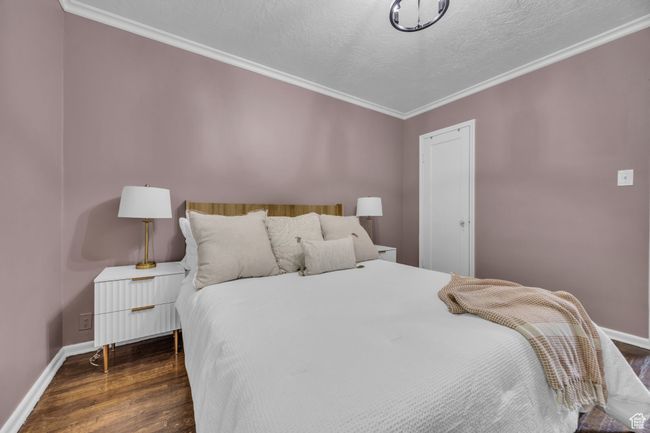 Bedroom with wood finished floors, ornamental molding, baseboards, and a textured ceiling | Image 14