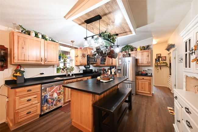 Kitchen with stainless steel appliances, dark countertops, dark wood finished floors, and a sink | Image 25