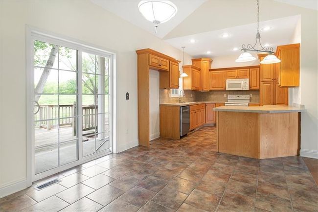 Kitchen with white appliances, baseboards, decorative backsplash, and light countertops | Image 19