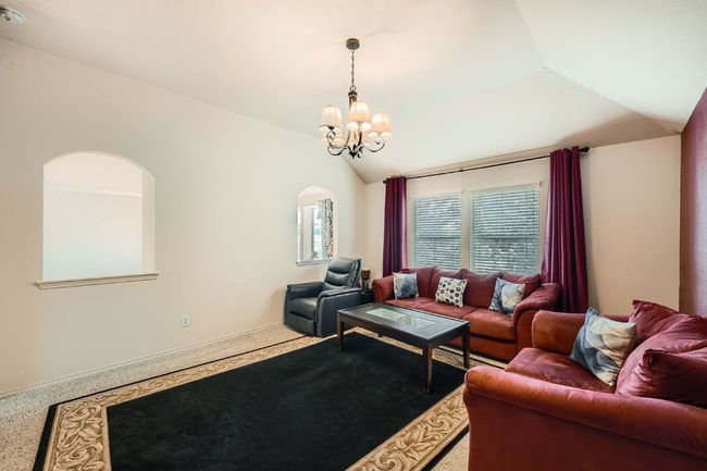 Living room featuring a chandelier, arched walkways, vaulted ceiling, and carpet | Image 29