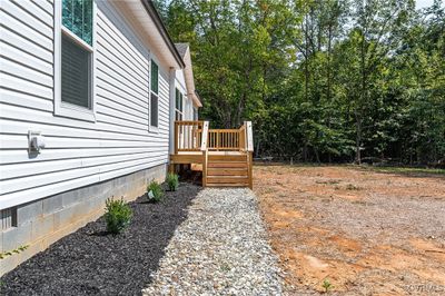 Path to front door with foundation landscaping, wooden front deck | Image 3