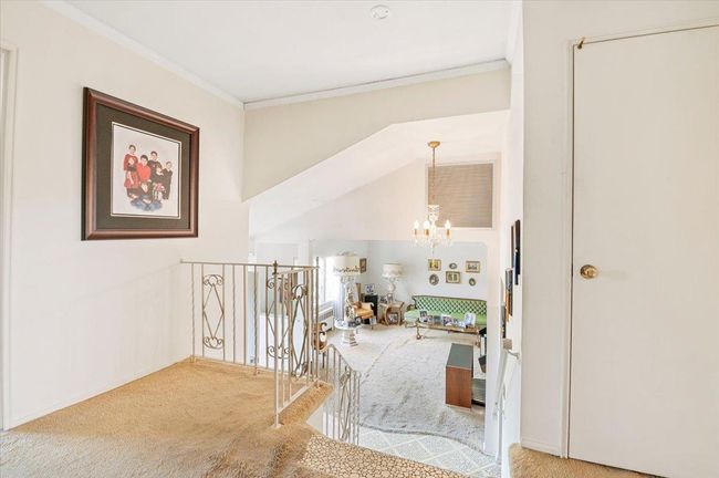 Hall with carpet flooring, ornamental molding, a chandelier, and an upstairs landing | Image 15