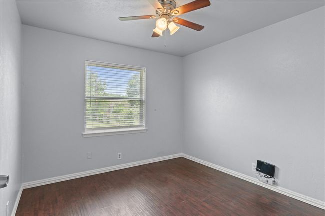 Empty room with dark wood finished floors and a ceiling fan | Image 14
