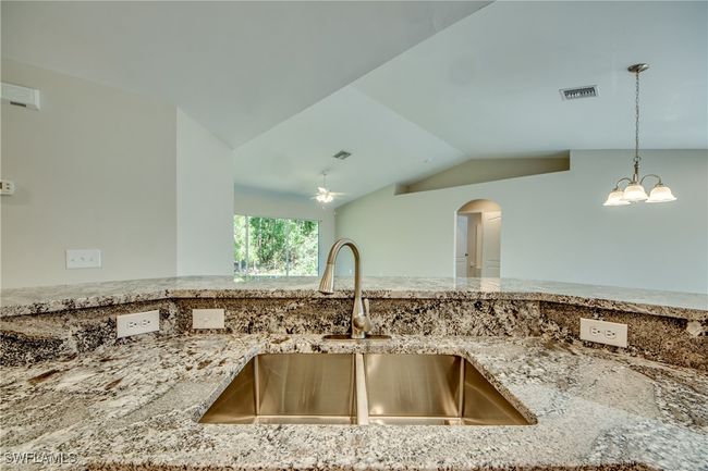 Kitchen featuring light stone counters, a sink, visible vents, and pendant lighting | Image 25