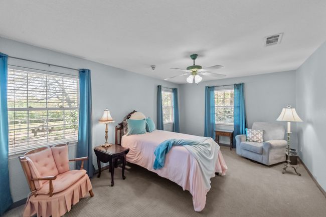 Bedroom featuring a ceiling fan, light carpet, baseboards, and visible vents | Image 24