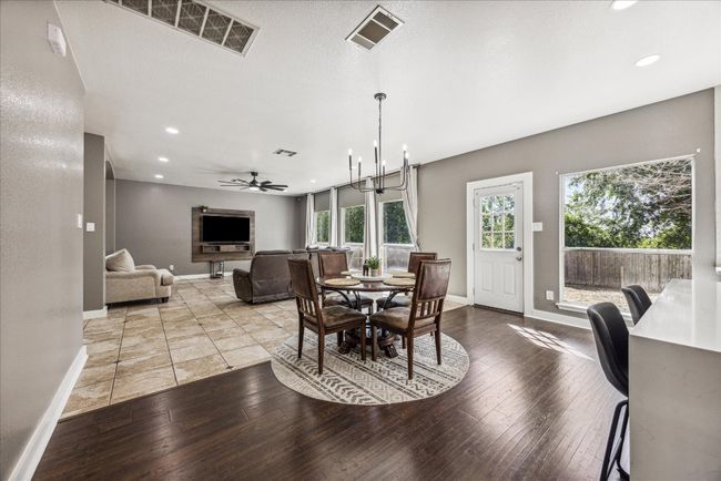 Dining room featuring wood-type flooring, visible vents, a ceiling fan, and baseboards | Image 12