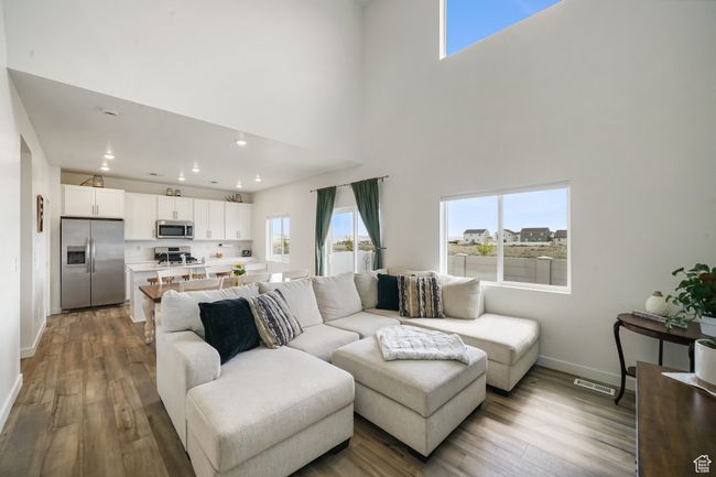 Living area with wood finished floors, baseboards, a towering ceiling, and recessed lighting | Image 8