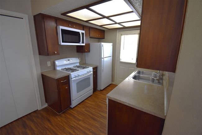 Kitchen featuring white appliances, dark wood-style floors, and light countertops | Image 4