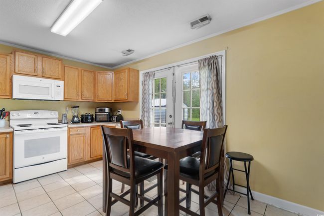 Kitchen featuring white appliances, light countertops, light tile patterned flooring, and ornamental molding | Image 9