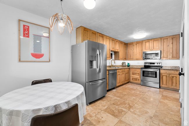 Kitchen featuring stainless steel appliances, stone counters, and a textured ceiling | Image 7