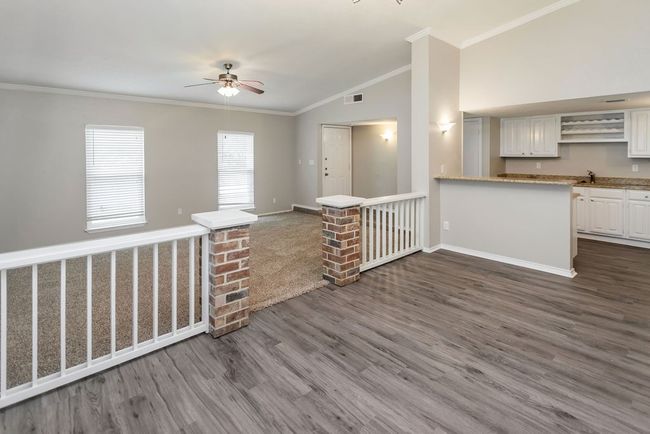 View of living, dining & wet bard area vaulted ceiling, white cabinets, ornamental molding, dark wood finished floors, and a peninsula | Image 10