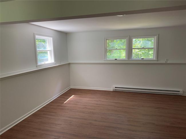 Unfurnished room featuring a baseboard heating unit and dark wood-type flooring | Image 8