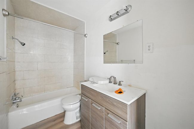 Bathroom featuring washtub / shower combination, vanity, toilet, and wood finished floors | Image 10