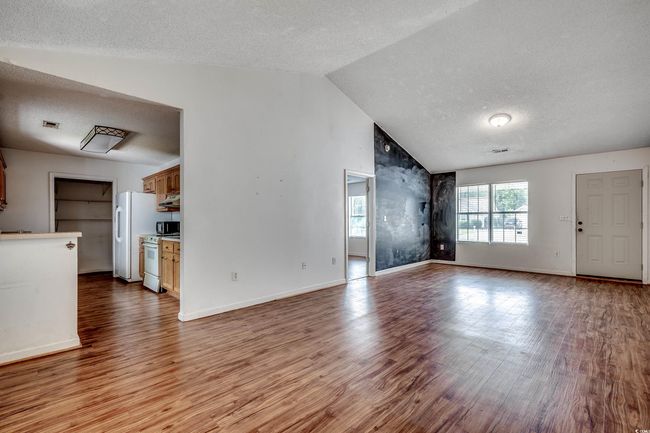Unfurnished living room with a textured ceiling, lofted ceiling, and wood finished floors | Image 22
