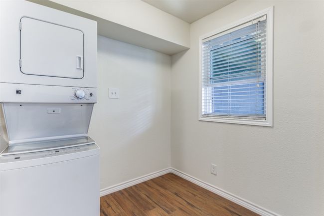 Laundry room with estacked washer and dryer, dark wood-style flooring, and baseboards | Image 9