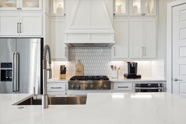 This sutnning streamlined kitchen offers upgraded finishes on pointe with designer trends, a huge center island, abundant cabinet and storage space with lighted, glass front uppers that extend to the ceiling. Pantry offers an electrical outlet to keep small appliances inside. | Image 14