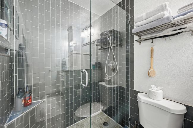 Bathroom with a stall shower and a textured wall | Image 27