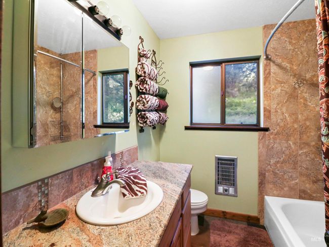 Full bathroom with vanity, heating unit, and shower / bathtub combination with curtain | Image 29