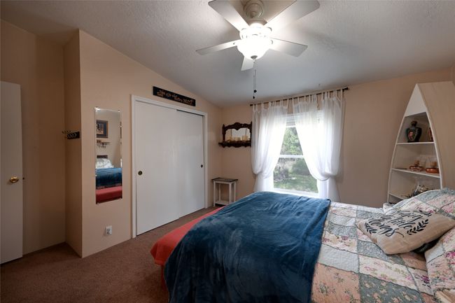 Bedroom with carpet, lofted ceiling, ceiling fan, a closet, and a textured ceiling | Image 42