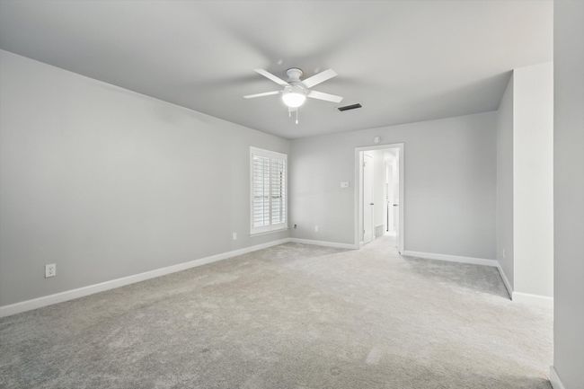 Primary bedroom with light colored carpet, baseboards, a ceiling fan, and visible vents | Image 20