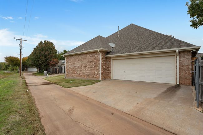 View of side of home with a shingled roof, concrete driveway, brick siding, and a yard | Image 37