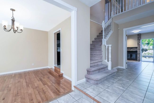 Stairway with a fireplace, baseboards, a chandelier, and wood finished floors | Image 4