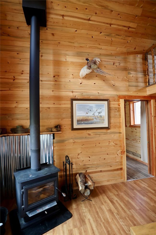 Detailed view of a wood stove, wood finished floors, and wooden walls | Image 4