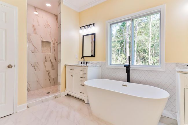 Bathroom featuring tile walls, ornamental molding, vanity, and independent shower and bath | Image 11