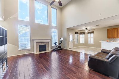 The family room has high ceilings, hand-scraped wood floors, gas log fireplace, and opens to the kitchen/breakfast room. | Image 2