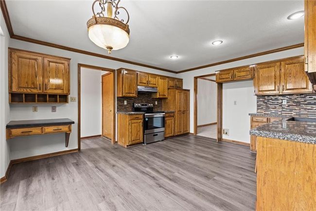 Kitchen with stainless steel range with electric stovetop, decorative backsplash, ornamental molding, and light hardwood / wood-style flooring | Image 12