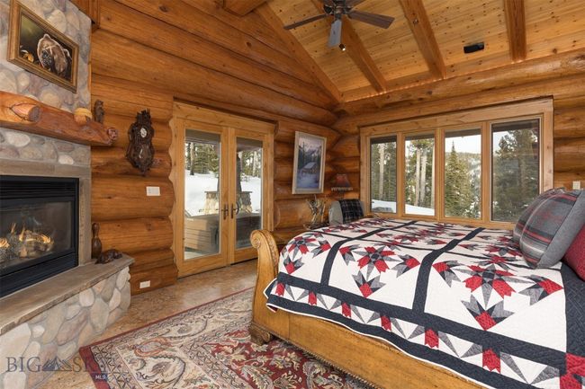 Main level primary bedroom with beamed ceiling, stone fireplace and access to outside hot tub patio. | Image 19