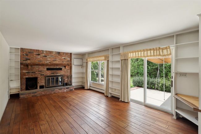Unfurnished living room with a baseboard heating unit, a fireplace, built in shelves, and hardwood / wood-style floors | Image 14