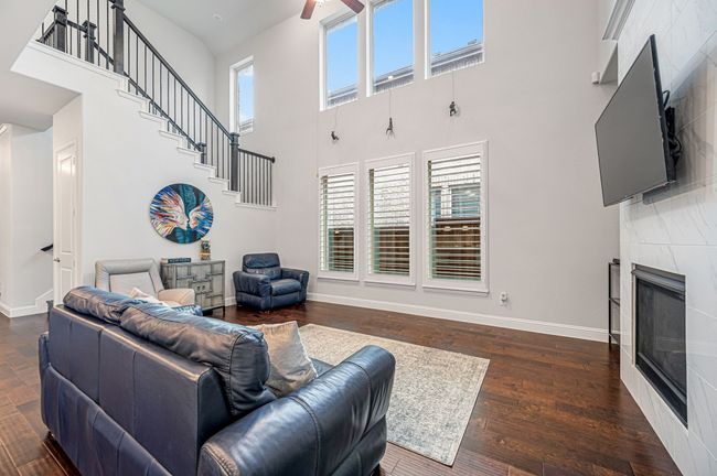 Living room featuring a premium fireplace, a ceiling fan, a healthy amount of sunlight, and a high ceiling | Image 19