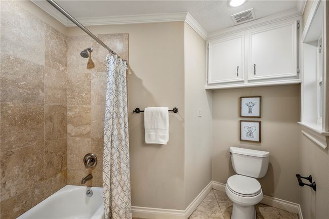 Full bathroom featuring toilet, visible vents, baseboards, ornamental molding, and shower / tub combo with curtain | Image 31