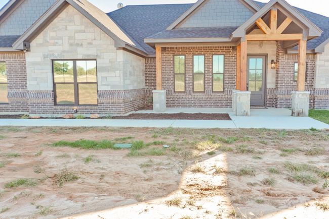 Back of property featuring brick siding, stone siding, and roof with shingles | Image 37