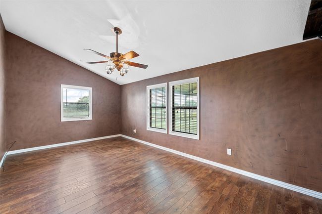 Spare room with healthy amount of natural light, dark wood-type flooring, ceiling fan, and lofted ceiling | Image 13