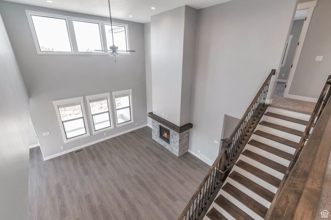 Unfurnished living room featuring a ceiling fan, wood finished floors, a glass covered fireplace, healthy amount of natural light, and recessed lighting | Image 21