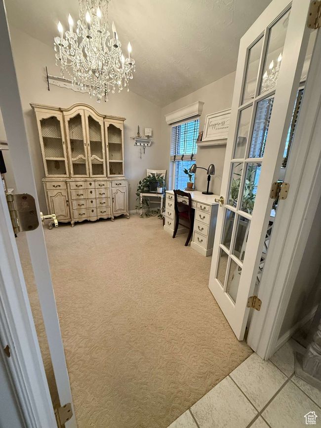 Home office with lofted ceiling, french doors, an inviting chandelier, and light carpet | Image 8