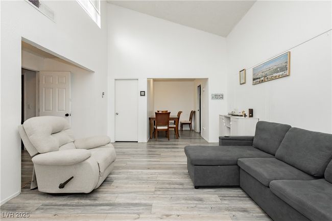 Living area with a towering ceiling and light wood-style floors | Image 7