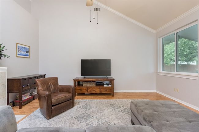 Living area with vaulted ceiling, wood finished floors, crown molding, and ceiling fan | Image 9