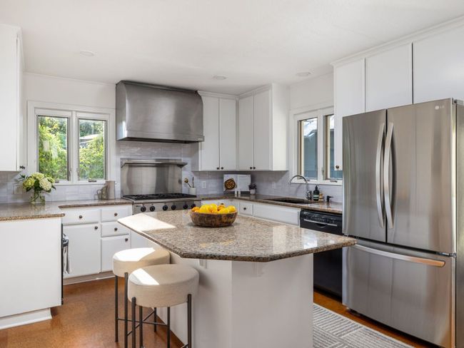 Kitchen with stainless steel refrigerator, kitchen island, & backsplash. | Image 9