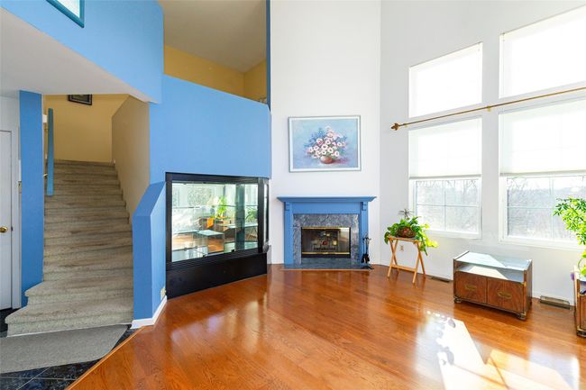 Unfurnished living room with a premium fireplace, hardwood / wood-style floors, built in cabinet, and a towering ceiling | Image 9