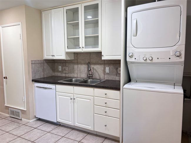 Laundry area featuring stacked washer / drying machine and light tile patterned floors | Image 4