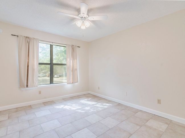 Empty room featuring a ceiling fan, a textured ceiling, baseboards, and light tile patterned floors | Image 10
