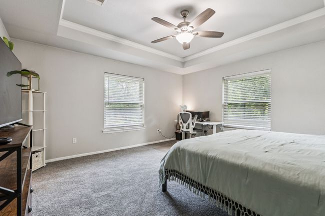 Carpeted bedroom featuring a tray ceiling, ornamental molding, and ceiling fan | Image 15