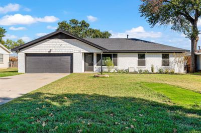 Ranch-style home featuring a garage and a front lawn | Image 1