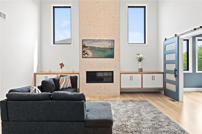 Living area with a fireplace, light wood-type flooring, and a barn door | Image 5
