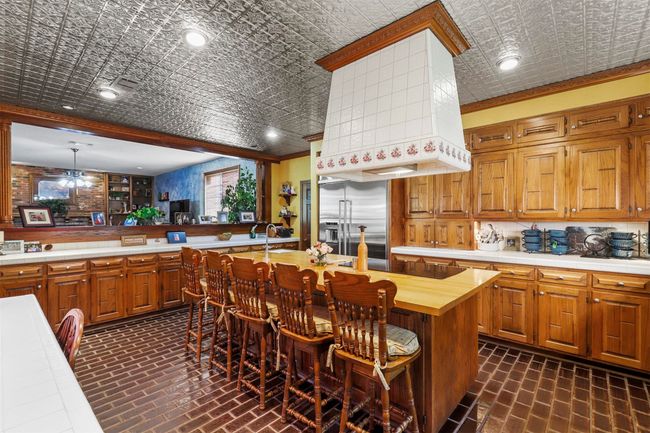 Kitchen with stainless steel built in refrigerator, decorative light fixtures, wooden counters, ornamental molding, and ceiling fan | Image 16