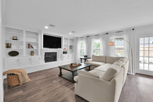 Enjoy gathering in the Living Room with a gas log fireplace, painted brick and hearth surround and built-in shelving & cabinets flanking the fireplace. | Image 6